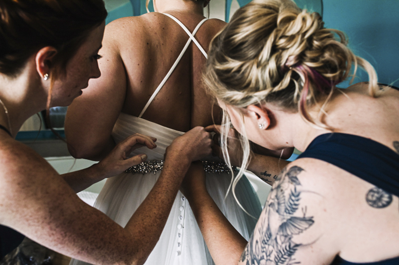 bridesmaids-helping-bride-get-dress-on